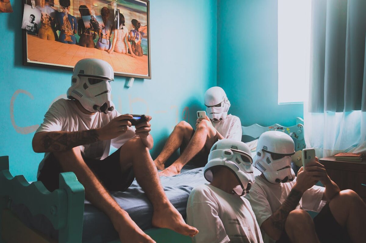 Four friends wearing helmets, playing video games indoors. Modern bedroom vibe.