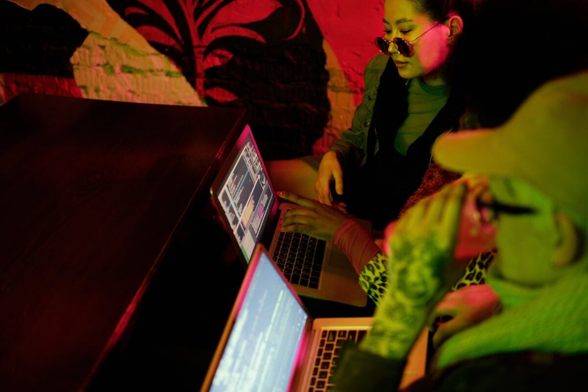 Attractiv Movies Young adults collaborating on coding projects in a trendy, dimly lit café setting.
